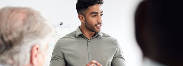 Man standing and presenting information a group of coworkers.