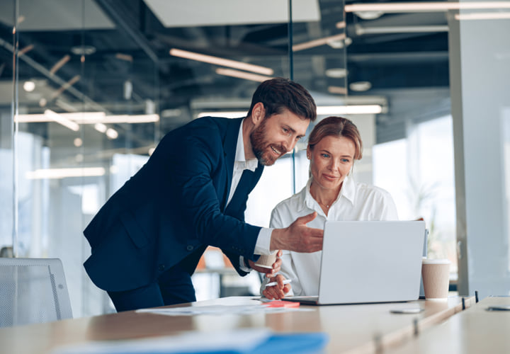 Two coworkers working together at a laptop.