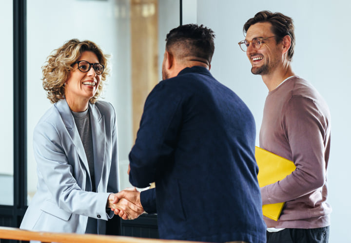 Three smiling coworkers shaking hands.