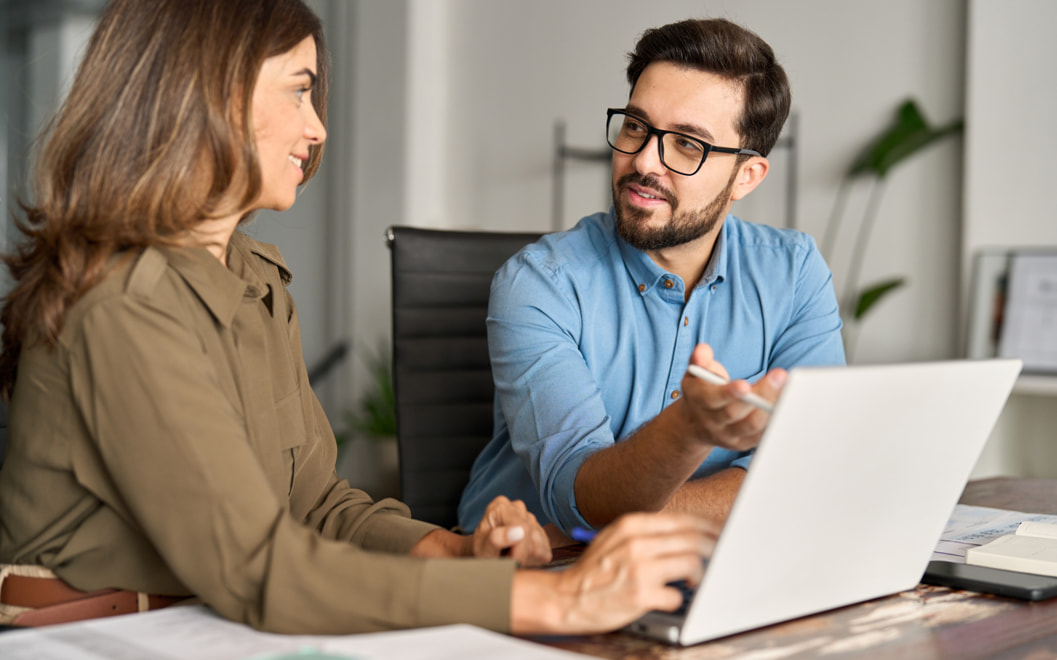 A man and a woman reviewing something on a laptop.