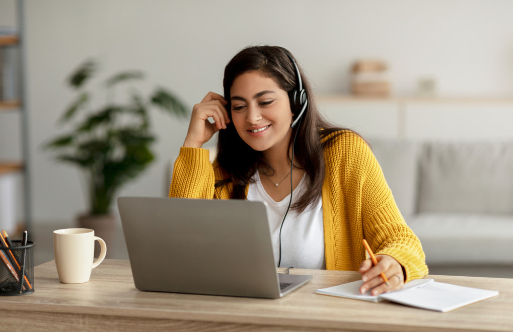 Woman wearing a headset while sitting in front of a laptop.