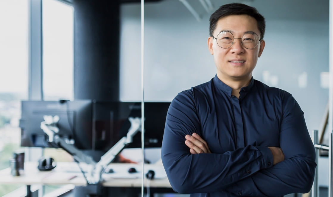 Confident individual contributor smiling with arms crossed, standing in a sleek, modern office.