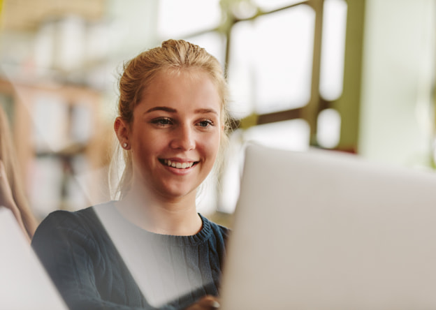 Smiling woman student working at a laptop