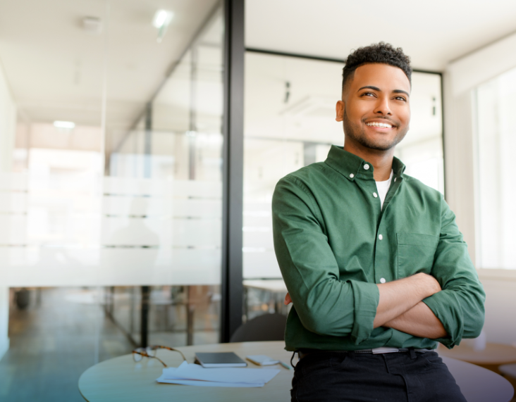 Man smiling with his arms folded in a contemporary office setting. A sample LPI Self report is in the bottom left corner.