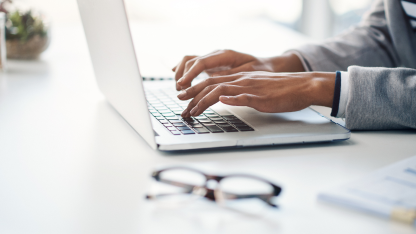 Close-up of a person’s hands typing on a laptop.